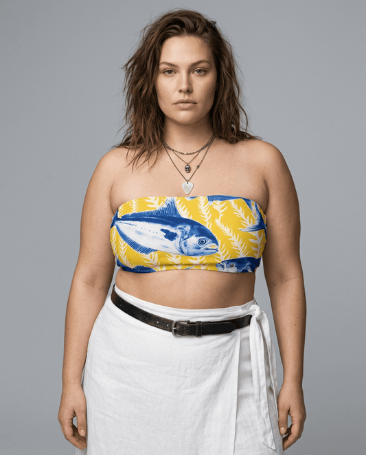 Woman wearing yellow Alacore bandeau top with blue fish print and layered necklaces