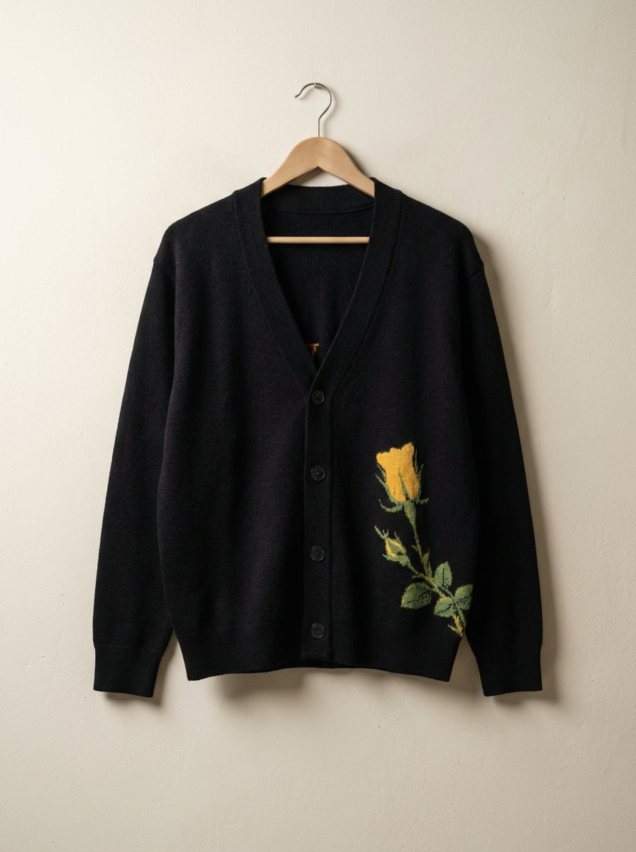 Black V-neck cardigan hanging showing ribbed trim and knitted rose design