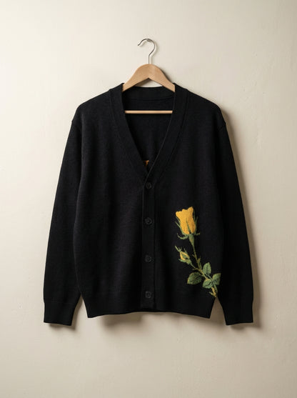 Black V-neck cardigan hanging showing ribbed trim and knitted rose design