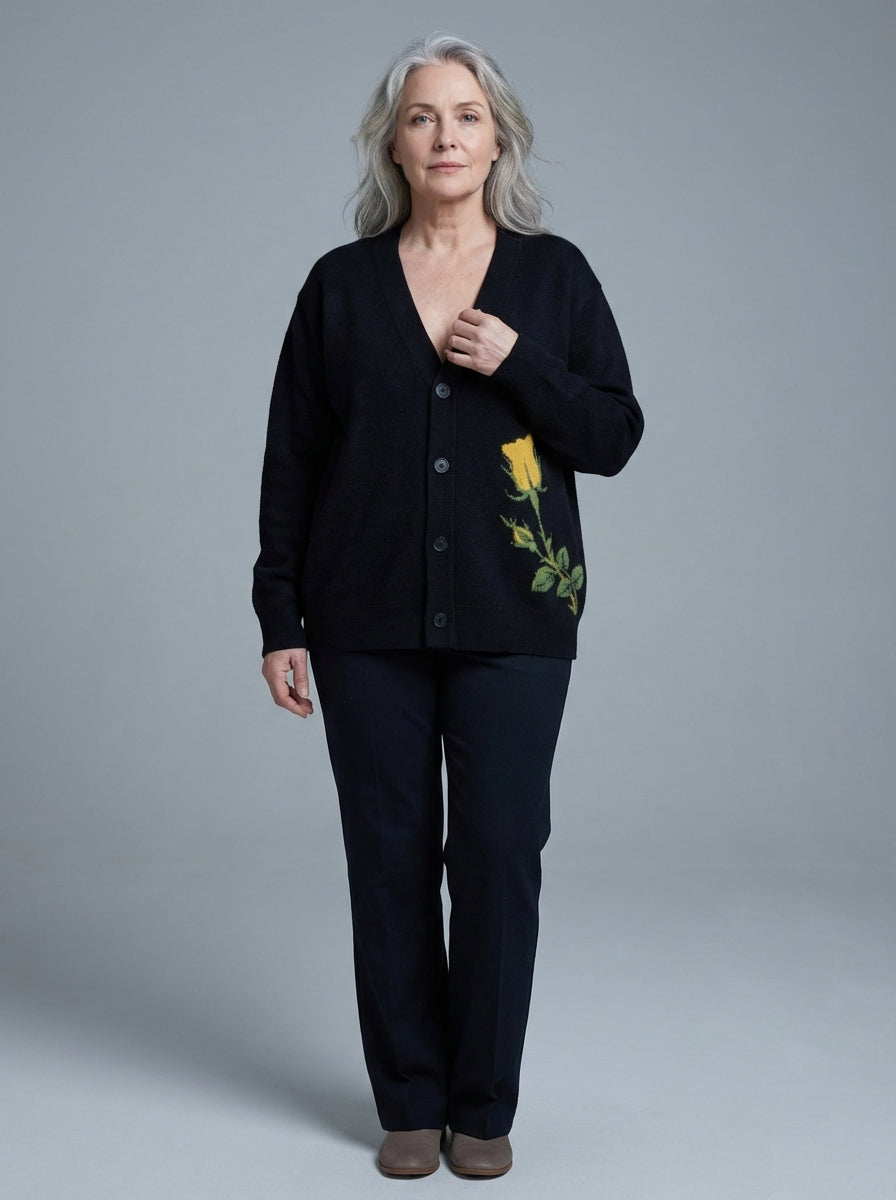 Woman wearing black knit cardigan with chest rose motif and dark pants