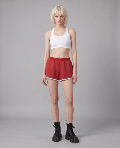 Model wearing red casual stretch shorts with white hem trim and natural waist fit