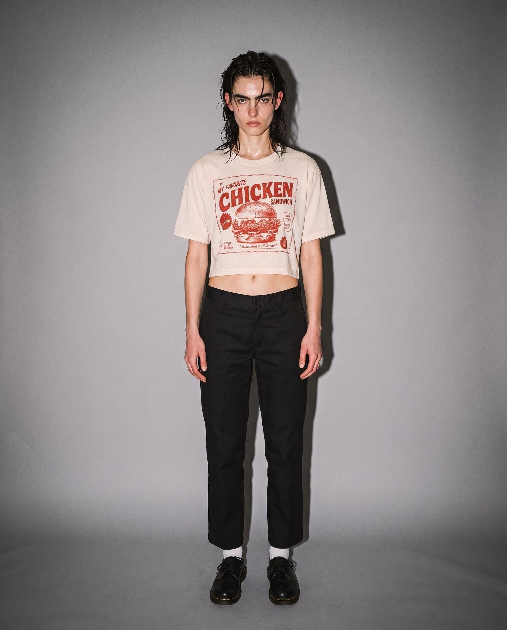 Woman wearing warm cream distressed chicken sandwich graphic crop tee with black pants