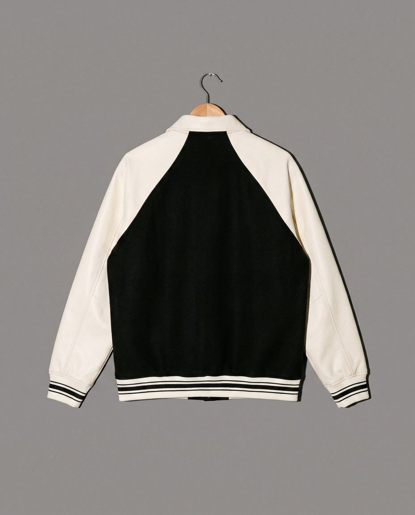 Black and cream varsity jacket back view with striped hem