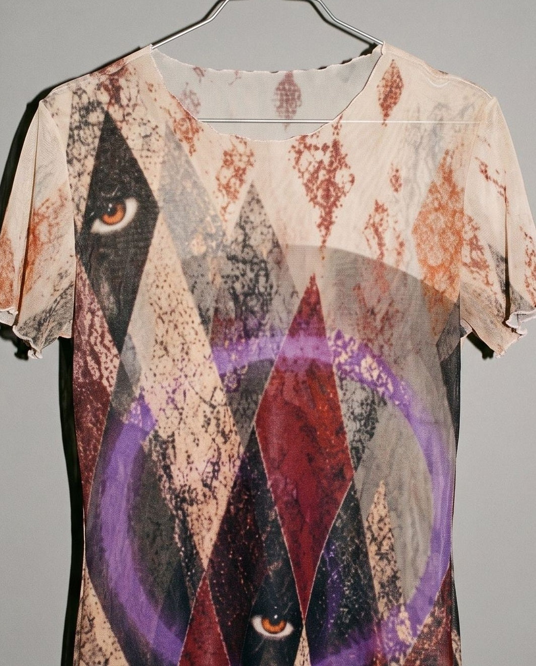 Close-up of HARLEQUIN mesh top featuring eye graphic and purple accent