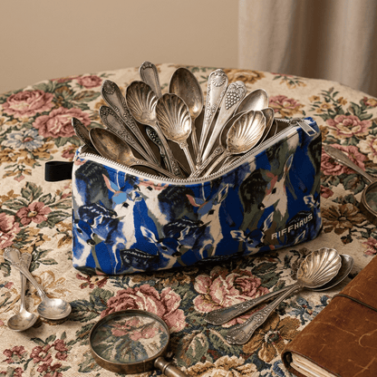 Open deer pattern pouch filled with vintage silver spoons