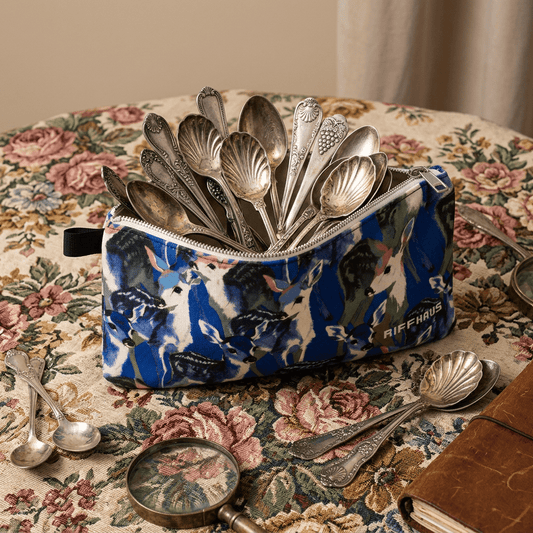 Open deer pattern pouch filled with vintage silver spoons