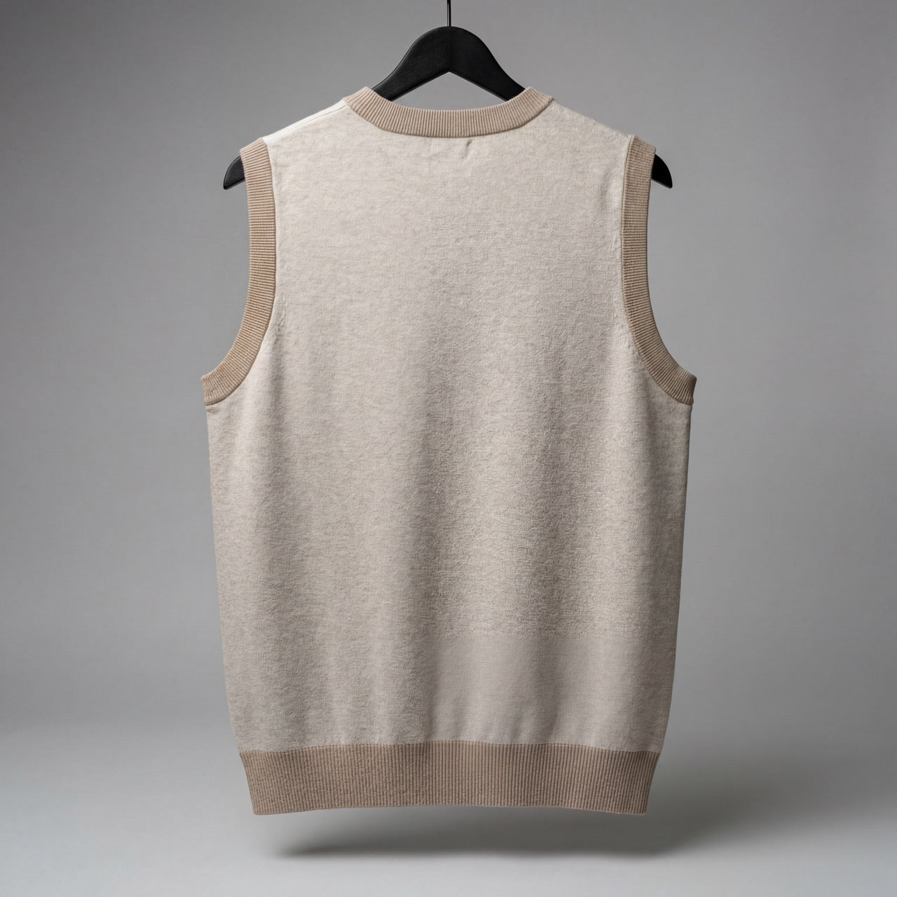 Back view of solid light beige sleeveless knit vest showing seamless construction and matching taupe ribbed trim