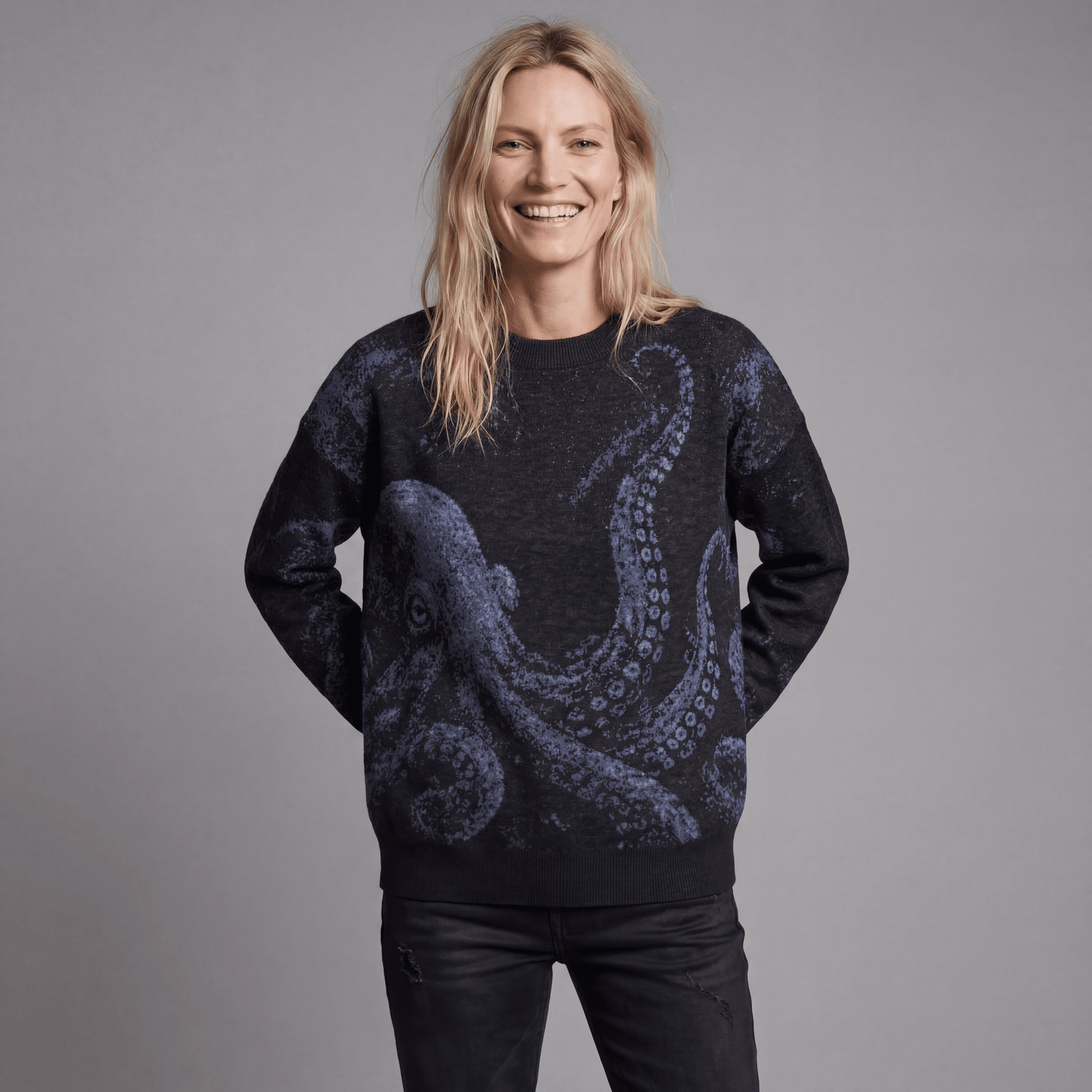 Smiling woman modeling Riffhaus KRAKEN dark heathered knit sweater with soft blue octopus design