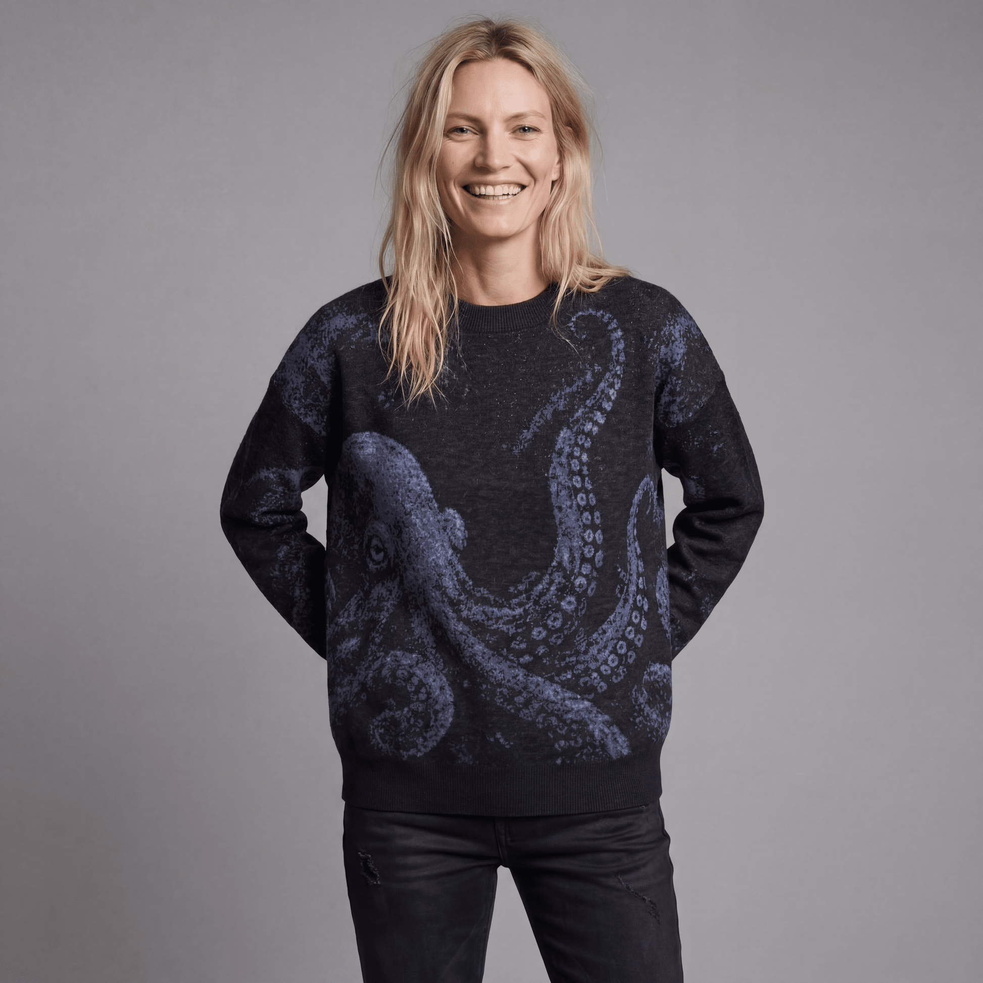 Smiling woman modeling Riffhaus KRAKEN dark heathered knit sweater with soft blue octopus design