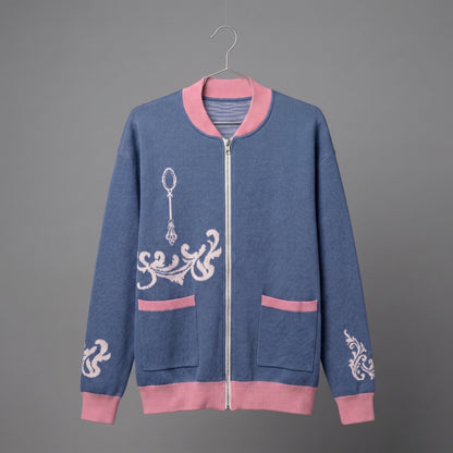 Front view of blue knit bomber jacket showing silver zipper, pockets, and ornate spoon jacquard motif