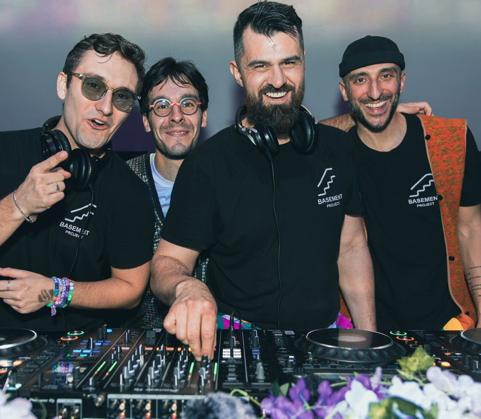 Group of DJs at a music event with equipment and flowers.