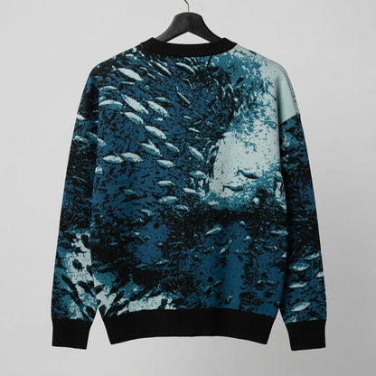 Back view of Riffhaus Sardine School knit sweater with flowing blue sardine pattern and black ribbed trim