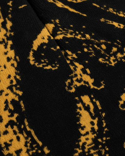 Close-up of black knit beanie texture and golden mushroom print detail