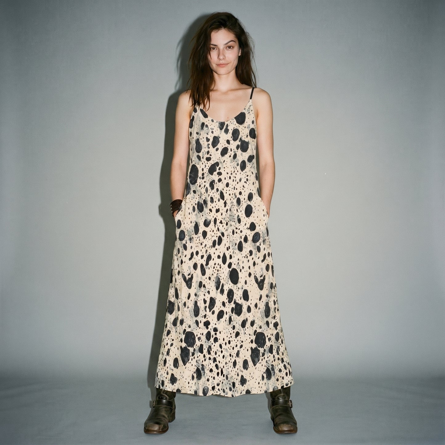 Front view of model in cream speckled long dress with hand in pocket