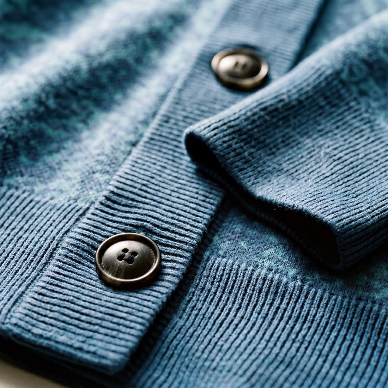 Close-up of brown matte buttons on blue-green tonal knit fabric