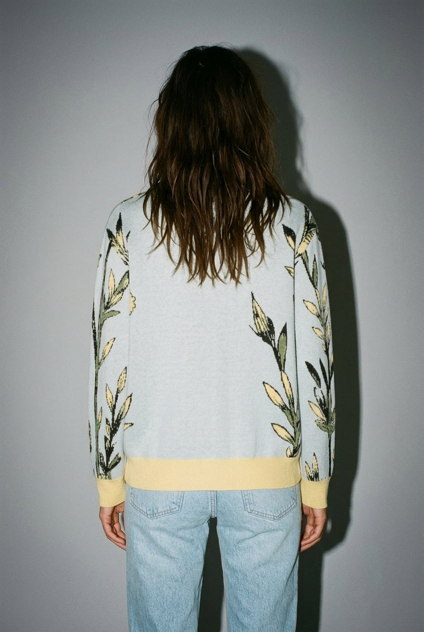 Back view of light blue cardigan with green stem pattern along sleeves