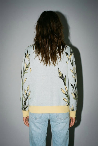 Back view of light blue cardigan with green stem pattern along sleeves