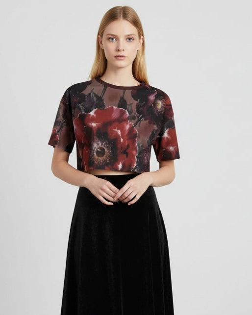 Woman wearing a black and red floral top with a plain background